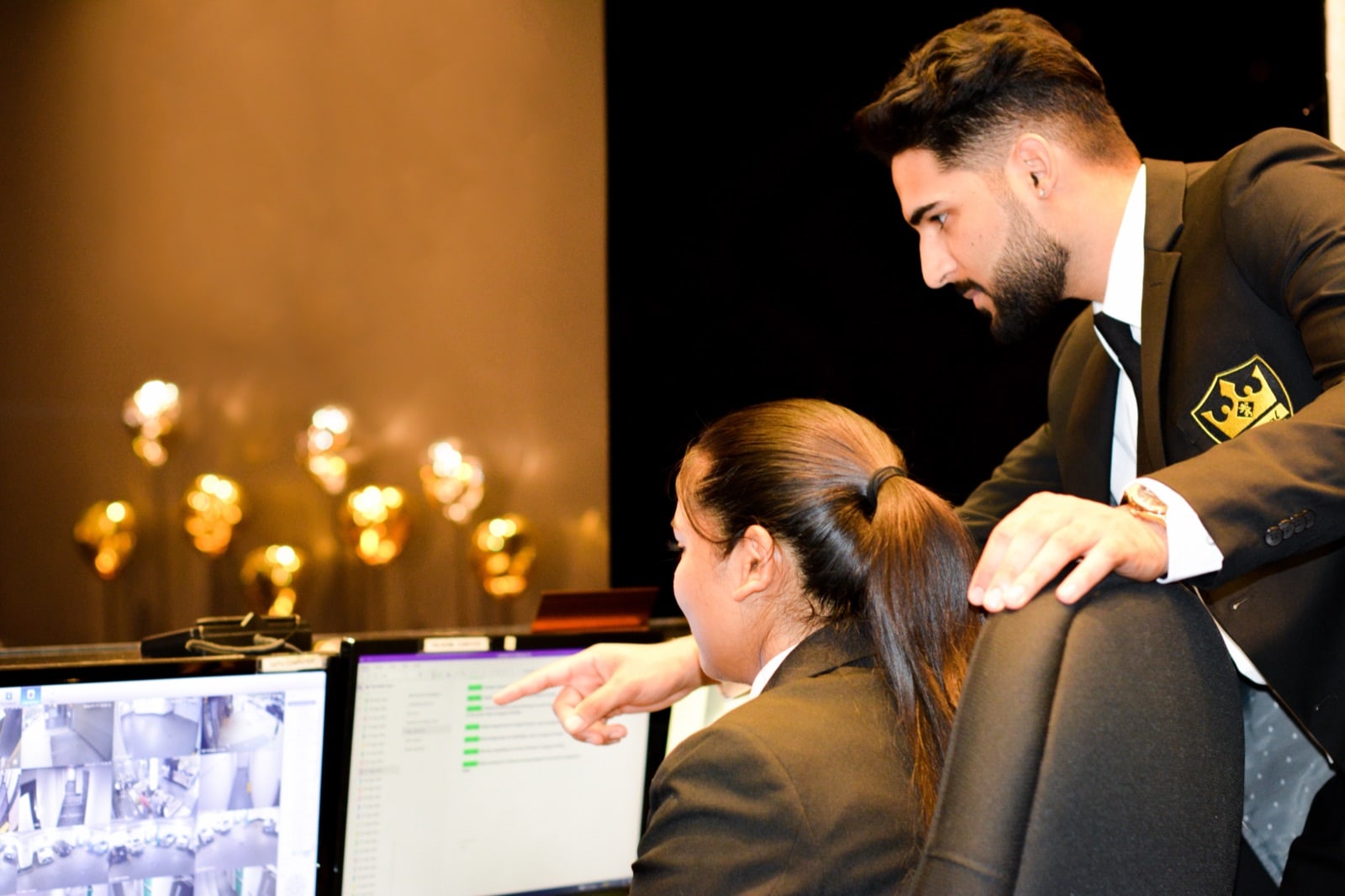 A Royal supervisor walking a concierge through the CCTV and access-control screens at the security desk
